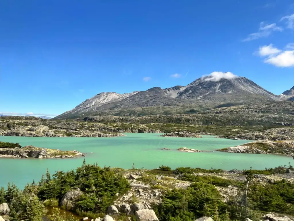 Lago entre montañas con cielo azul y nubes blancas
