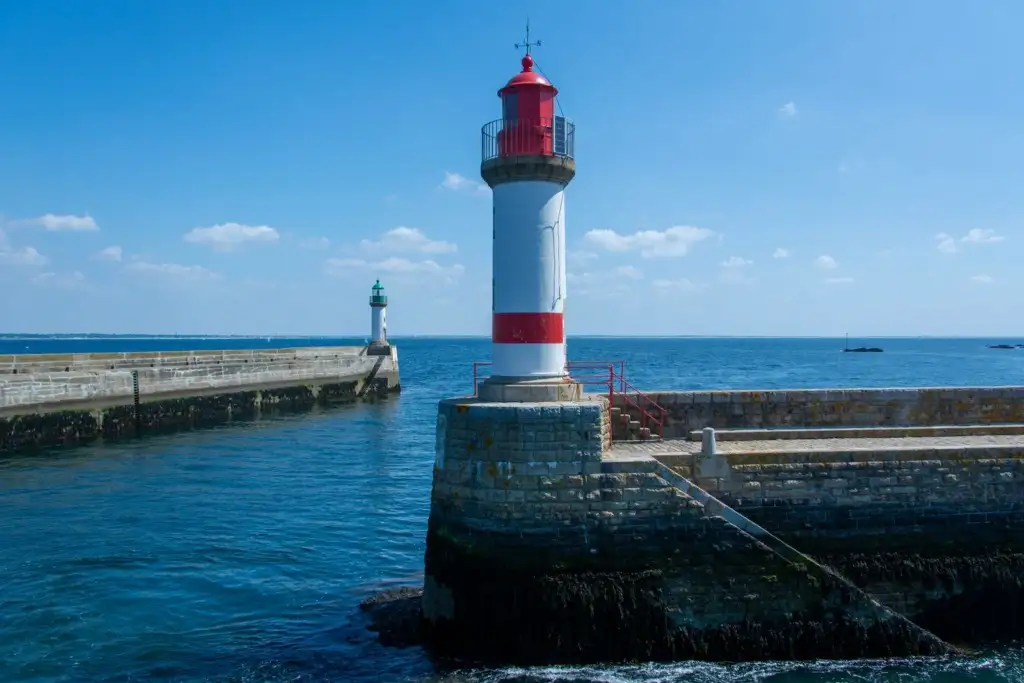 Dos faros en un muelle de piedra frente al mar bajo un cielo azul