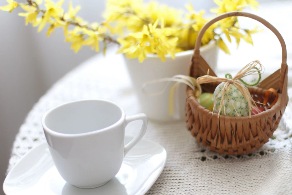 Taza blanca de café junto a flores amarillas