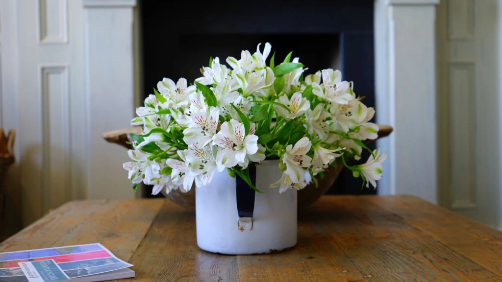 Ramo de flores blancas en una cubeta sobre una mesa de madera