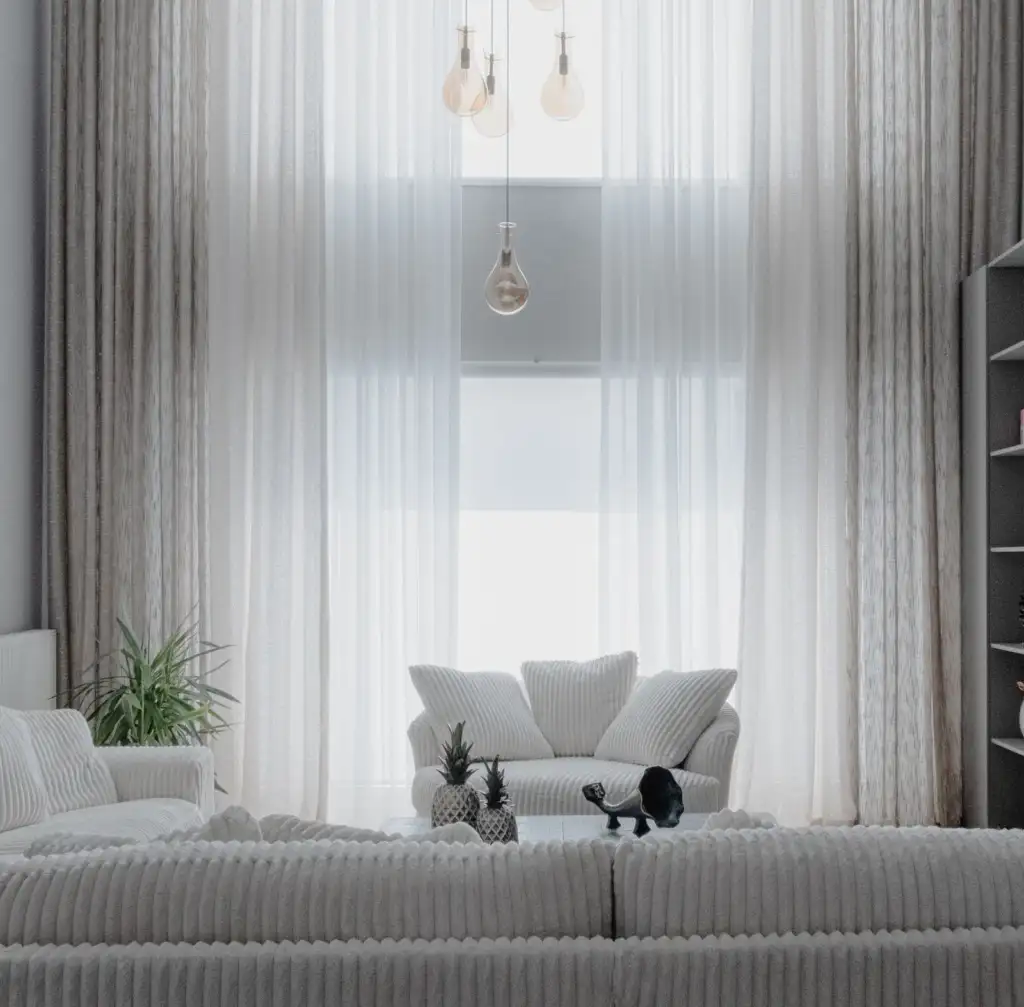 Sala luminosa con sofá blanco y cortinas claras